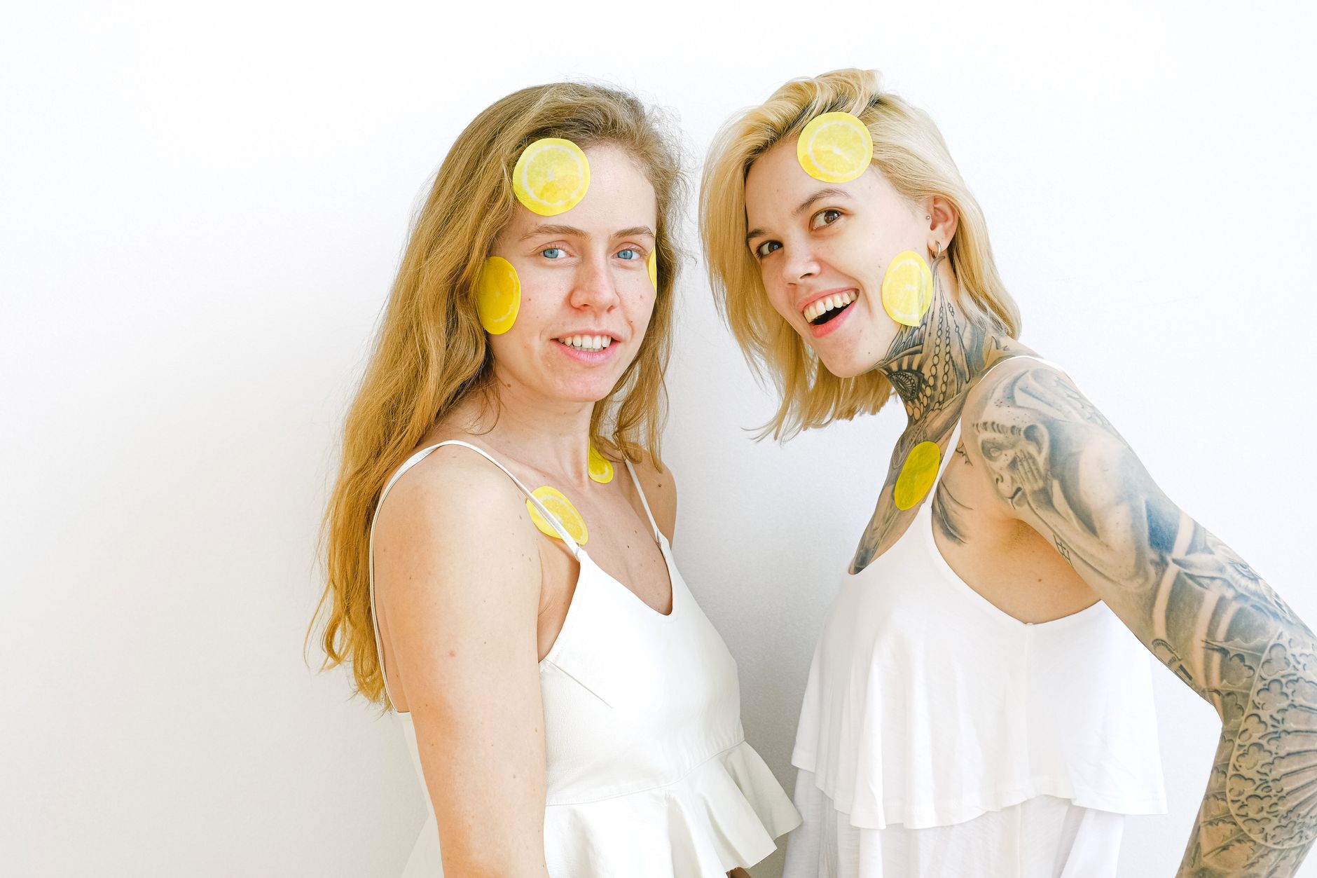 A bright lemon clitoral vibrator surrounded by fresh citrus and flowers on a vibrant yellow background