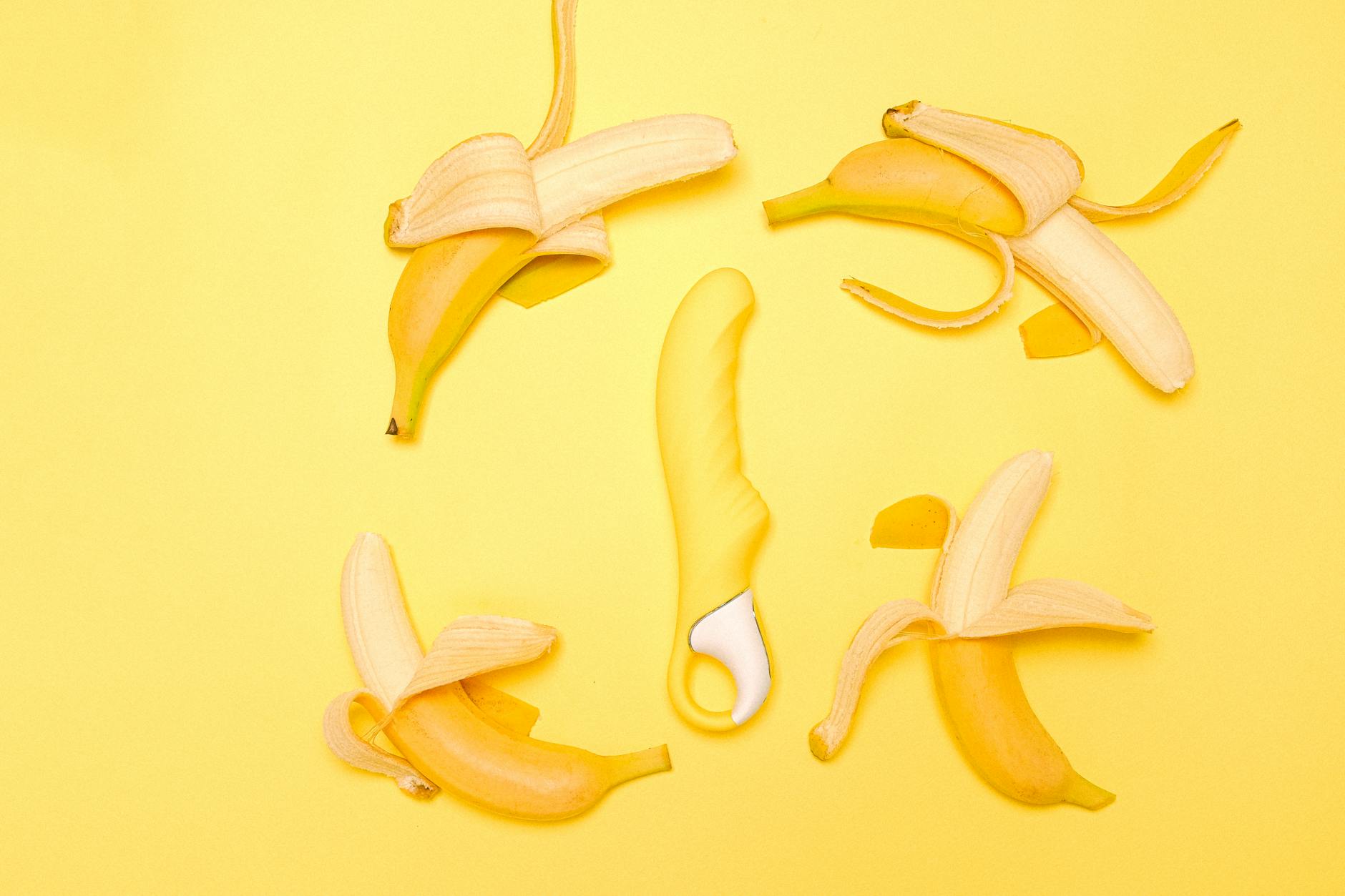 Yellow lemon clitoral vibrator displayed with fresh lemons on a bright yellow background