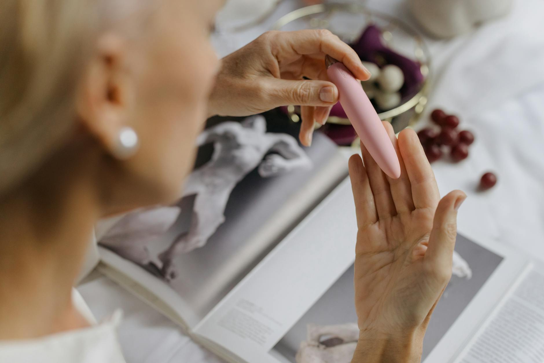 Close-up of a hand holding a pink vibrator against an intimate setting, emphasizing personal pleasure and comfort.