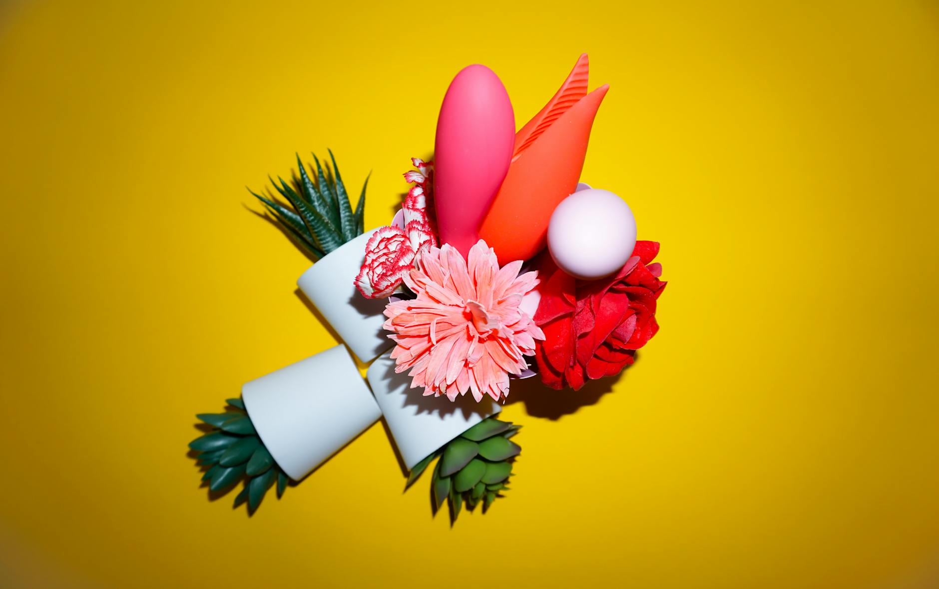 Yellow silicone vibrator surrounded by peeled bananas on a bright yellow background