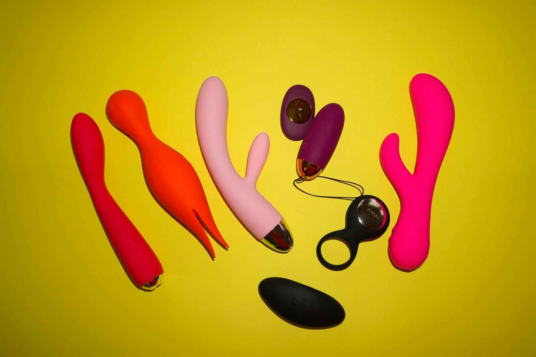 Colorful clitoral vibrators including a lemon-shaped toy on a bright yellow background