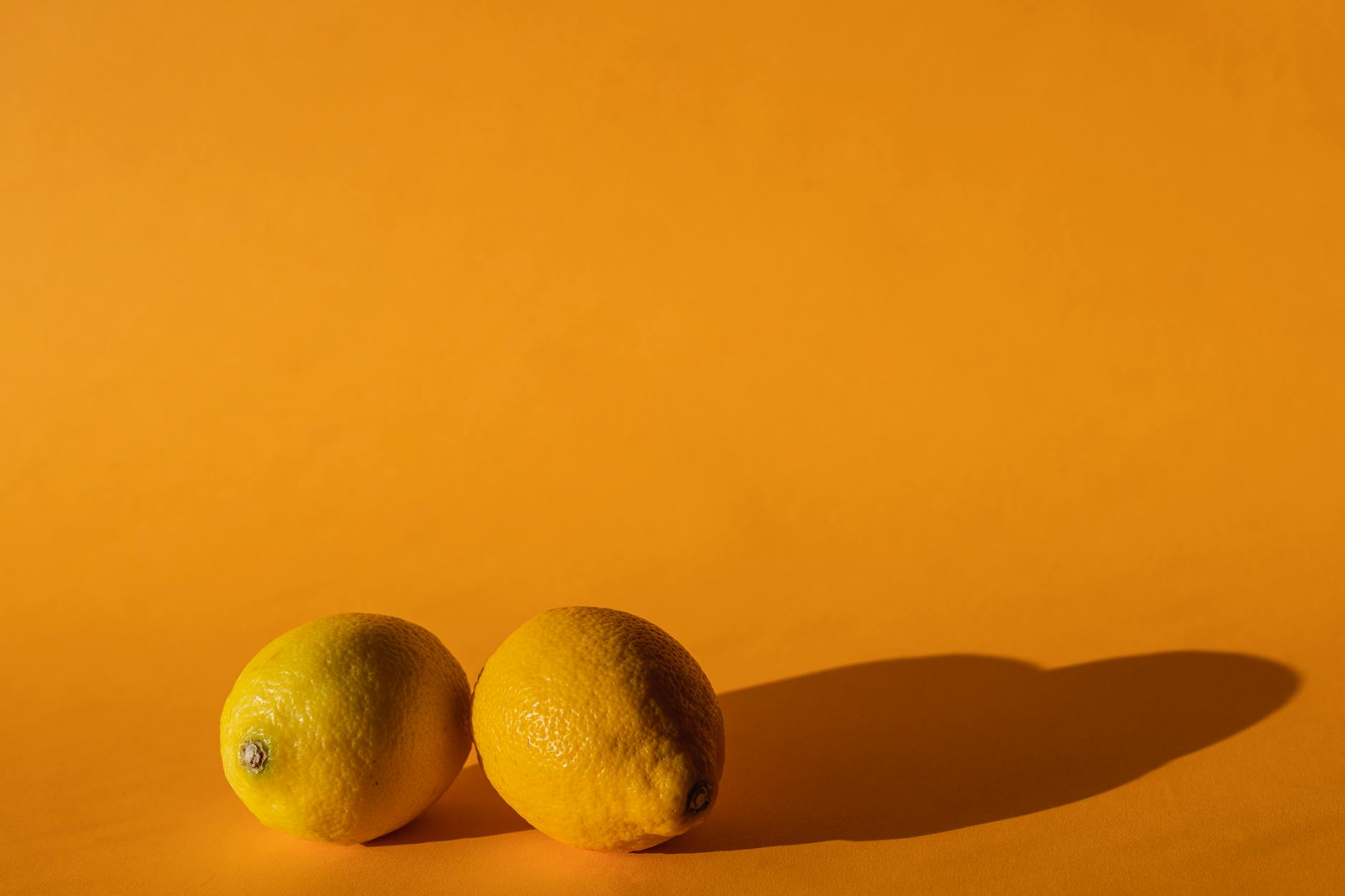 Ripe vivid lemons on a yellow background showcasing bright daylight studio photography
